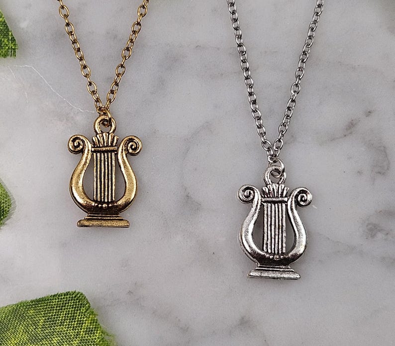Op de afbeelding: Twee gouden en zilveren kettingen met een lier hanger. De lier is een snaarinstrument.