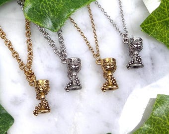 May include: Four necklaces with chalice pendants. Two are gold-toned, and two are silver-toned. Each chalice has a detailed design with grapes and decorative patterns. The chains are delicate, and the pendants are small, making them suitable for everyday wear.