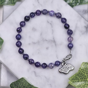Peut inclure: Bracelet en perles d'agate violettes avec un charme argenté qui dit "DREAMS".