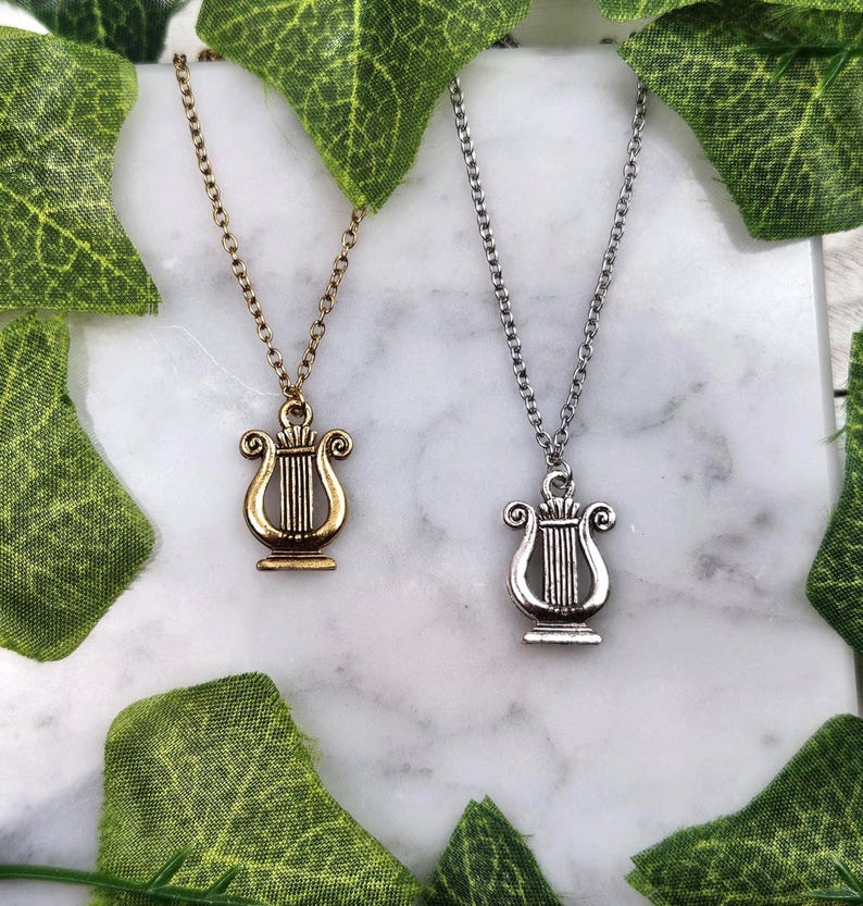 Op de afbeelding: Twee zilveren kettingen met een lier hanger. De ene ketting heeft een gouden lier hanger en de andere een zilveren lier hanger.