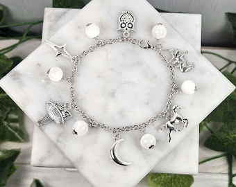 May include: A silver charm bracelet with white beads and various charms, including an owl, a crescent moon, a star, a unicorn, and a mushroom.