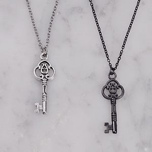 Puede incluir: Dos collares con llaves de plata, uno con una cadena de plata y otro con una cadena negra. Ambas llaves tienen un dise&ntilde;o adornado.