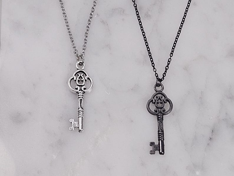 Puede incluir: Dos collares con llaves de plata, uno con una cadena de plata y otro con una cadena negra. Ambas llaves tienen un dise&ntilde;o adornado.