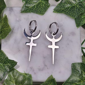 May include: A pair of silver earrings with a crescent moon and a dagger design.
