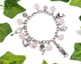 May include: A silver charm bracelet with pink beads and various charms, including a heart, a rose, a seashell, a mirror, a dolphin, and a crown.