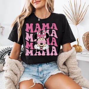 May include: Black t-shirt with a pink and white graphic of Minnie Mouse with the text "Mama Mia" repeated in a retro font.