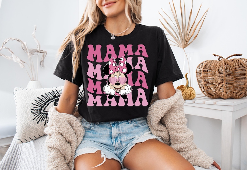 May include: Black t-shirt with a pink and white graphic of Minnie Mouse with the text "Mama Mia" repeated in a retro font.