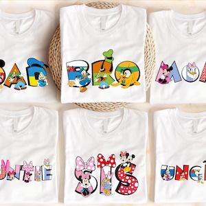 six white t-shirts with various Disney character names and illustrations printed on them.