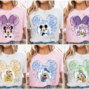 Könnte beinhalten: Sechs kurzärmelige T-Shirts mit Disney-Figuren. Jedes Shirt hat einen Mickey Mouse-Kopfumriss mit einer Figur im Inneren. Zu den Figuren gehören Minnie Mouse, Mickey Mouse, Daisy Duck, Pluto, Donald Duck und Goofy.