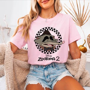 A woman wearing a pink t-shirt with a cartoon character and the text "Disney Zooopia 2" printed on it.
