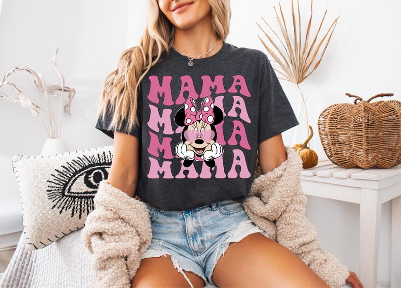 May include: A dark grey t-shirt with a pink and white graphic of Minnie Mouse wearing heart-shaped sunglasses and the text "MAMA" repeated four times.