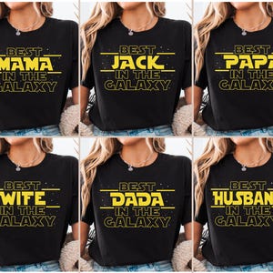 May include: Six black t-shirts with yellow text that reads "Best [Title] in the Galaxy". The titles are Mama, Jack, Papa, Wife, Dada, and Husband.
