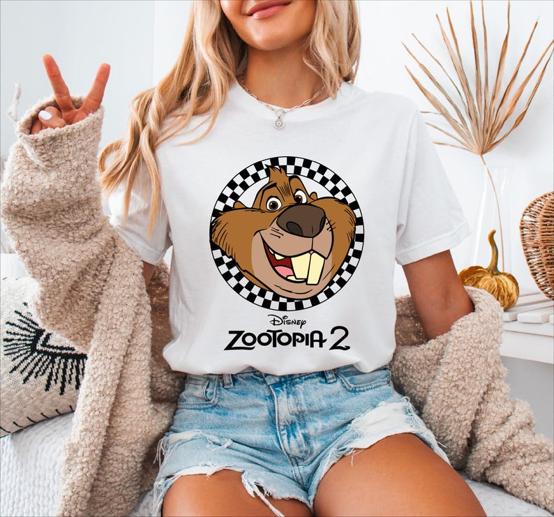 A woman wearing a white t-shirt with a cartoon character and the text "Disney Zootopia 2" printed on it.