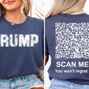 May include: A navy blue t-shirt with the word "TRUMP" printed in white on the front and a QR code with the text "SCAN ME! You won't regret it." printed in white on the back.