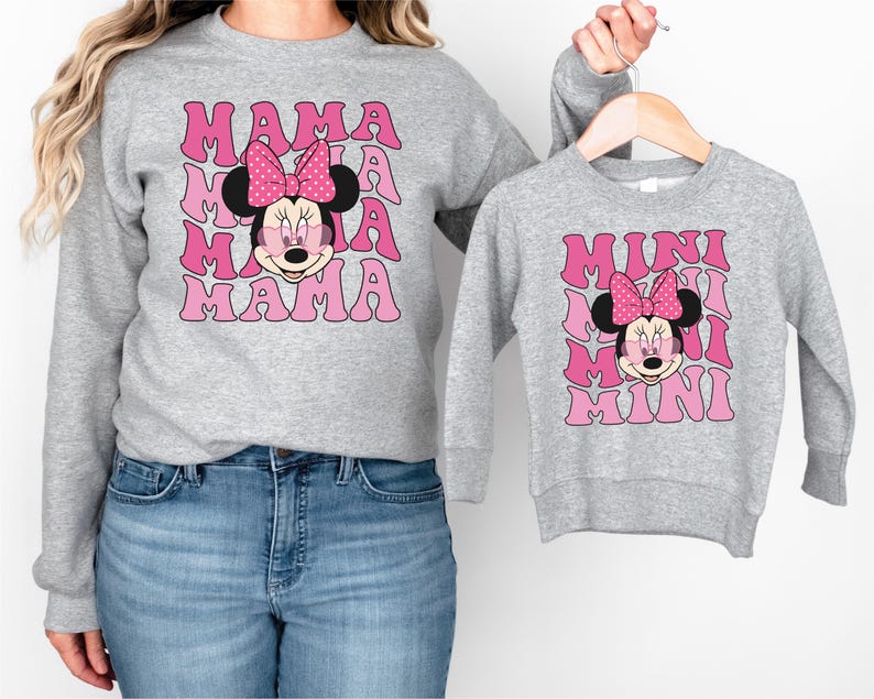 a woman wearing a mickey mouse sweatshirt and a minnie mouse sweatshirt