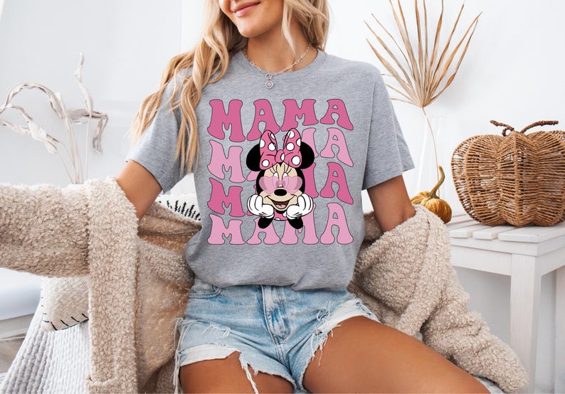 May include: A gray t-shirt with a pink and white graphic of Minnie Mouse with the word "MAMA" repeated in pink letters.