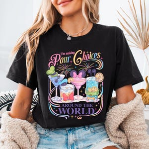 May include: Black t-shirt with a colorful graphic of cocktails and the text "I'm making Pour Choices Around the World." The design features cartoon cocktails with mouse ears and bows.