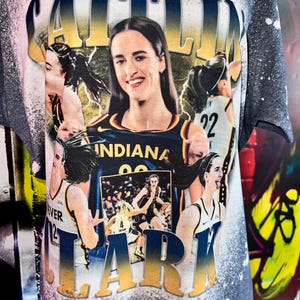Puede incluir: Una camiseta azul y dorada con un aspecto desgastado que presenta un collage de im&aacute;genes de una jugadora de baloncesto. El nombre de la jugadora, "Caitlin Clark", est&aacute; escrito en letras doradas grandes en la parte superior de la camiseta. La camiseta tambi&eacute;n presenta las palabras "Indiana" y "22".