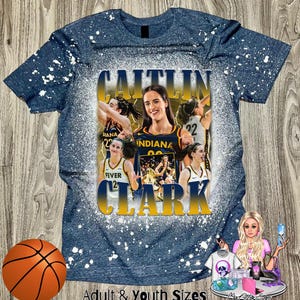 Puede incluir: Una camiseta azul con un dise&ntilde;o de salpicaduras blancas. La camiseta presenta un collage de jugadoras de baloncesto con el texto "CAITLIN CLARK" en letras amarillas.