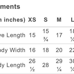 K&ouml;nnte beinhalten: Eine Gr&ouml;&szlig;entabelle mit dem Titel Measurements in inches, die Kleidungsma&szlig;e f&uuml;r die Gr&ouml;&szlig;en XS bis 2XL auflistet. Die Tabelle enth&auml;lt Zeilen f&uuml;r &Auml;rmell&auml;nge, K&ouml;rperbreite und K&ouml;rperl&auml;nge mit spezifischen numerischen Werten in Zoll f&uuml;r jede Gr&ouml;&szlig;e.