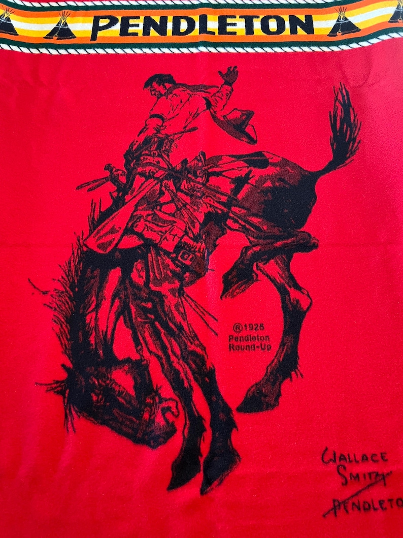 Puede incluir: Textil rojo con una ilustraci&oacute;n negra de un vaquero montando un bronco. El borde superior muestra la palabra "PENDLETON" sobre un dise&ntilde;o de inspiraci&oacute;n nativa americana. Tambi&eacute;n se ve el texto "@1925 Pendleton Round-Up" y la firma "Wallace Smith Pendleton".