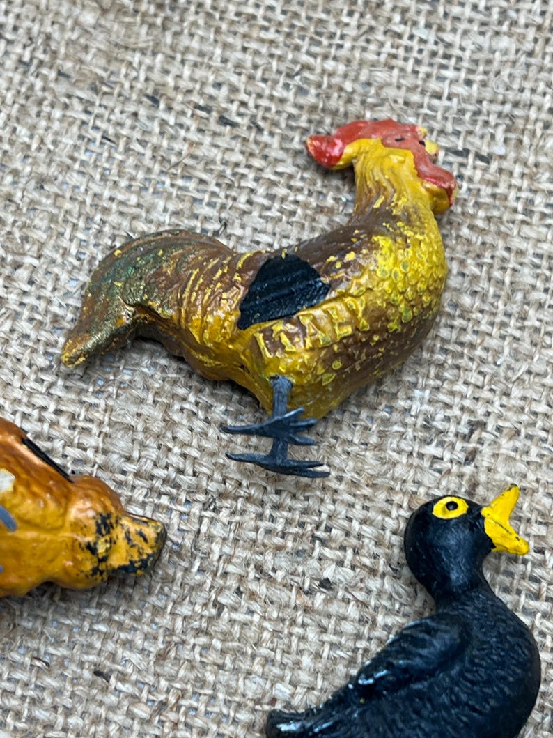 K&ouml;nnte beinhalten: Nahaufnahme einer bunten Hahnenfigur mit rotem Kamm, gelbem K&ouml;rper und braunen und schwarzen Akzenten. Das Wort "ITALY" ist auf der Figur zu sehen. Der Hahn ist Teil einer Sammlung von Tierfiguren.