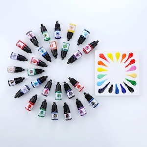 May include: A collection of twenty-four small plastic squeeze bottles filled with various coloured liquid dyes, arranged in a circular pattern. Beside the bottles is a square white palette featuring twenty-four corresponding colourful paint drops.