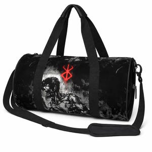 May include: Black duffel bag with a grayscale illustration of a muscular figure and a red symbol. The bag has black handles and a shoulder strap. The cylindrical bag is designed for carrying items.