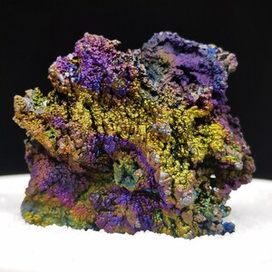 Könnte beinhalten: Ein großes, irisierendes, violettes, grünes und goldenes Mineralstück mit einer rauen, strukturierten Oberfläche.