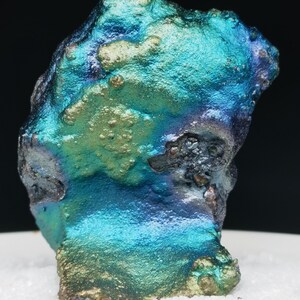 Könnte beinhalten: Ein großes, irisierendes, blaues, grünes und violettes Mineralstück mit einer rauen, strukturierten Oberfläche.