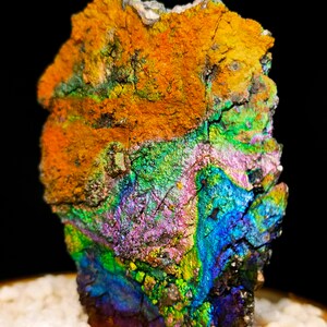 Könnte beinhalten: Ein großer, irisierender Stein mit einer rauen, strukturierten Oberfläche. Der Stein zeigt eine Vielzahl von Farben, darunter Orange, Grün, Blau und Lila.