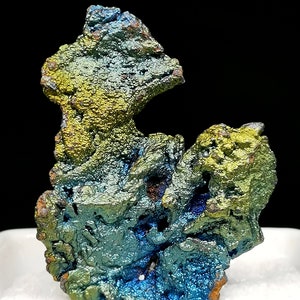Puede incluir: Un gran espécimen mineral iridiscente azul, verde y dorado. El mineral tiene una superficie rugosa y texturizada y parece ser una formación natural.
