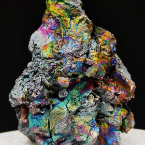 Könnte beinhalten: Ein großer, irisierender, grauer Stein mit einer rauen, strukturierten Oberfläche. Der Stein hat einen Regenbogen aus Farben, darunter Blau, Grün, Gelb und Lila.