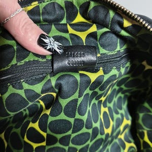 Detailaufnahme der Seriennummer und des grünen Innenfutters der Vintage Gucci Tasche.