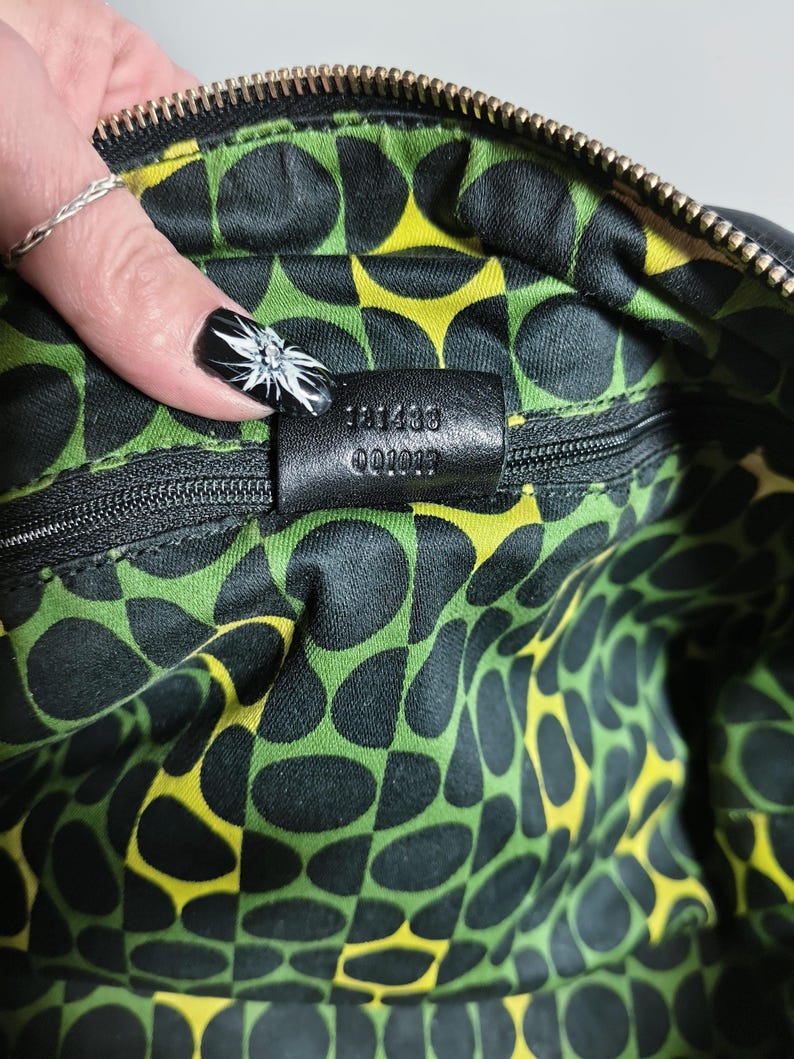Detailaufnahme der Seriennummer und des grünen Innenfutters der Vintage Gucci Tasche.