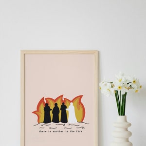 Puede incluir: Una impresión enmarcada con un fondo melocotón que presenta una ilustración estilizada de cuatro figuras de pie en un fuego. Las figuras son siluetas negras con una figura blanca. El texto "there is another in the fire" está impreso debajo de la ilustración.