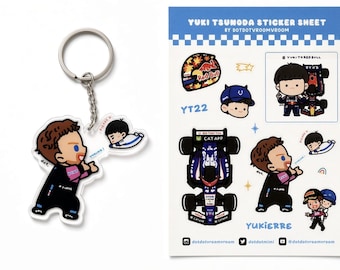Può includere: Un portachiavi in acrilico con un personaggio dei cartoni animati in tuta da corsa e un foglio di adesivi intitolato Yuki Tsunoda Sticker Sheet by dotdotvroomvroom con varie illustrazioni di un'auto da corsa e un casco.