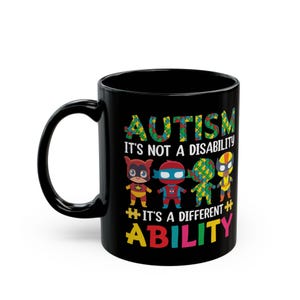 Puede incluir: Taza de café negra con un diseño blanco que dice "Autismo No es una discapacidad Es una habilidad diferente" con cuatro superhéroes de dibujos animados en el medio. Los superhéroes llevan trajes rojo, azul, amarillo y verde.