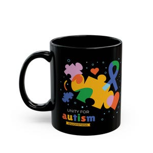 Puede incluir: Taza de café de cerámica negra con un diseño de pieza de rompecabezas colorido y el texto "Unity for autism awareness".