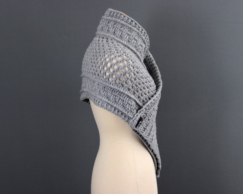 May include: Gray crochet shawl with a lacy pattern and a textured border. The shawl is draped over a mannequin.