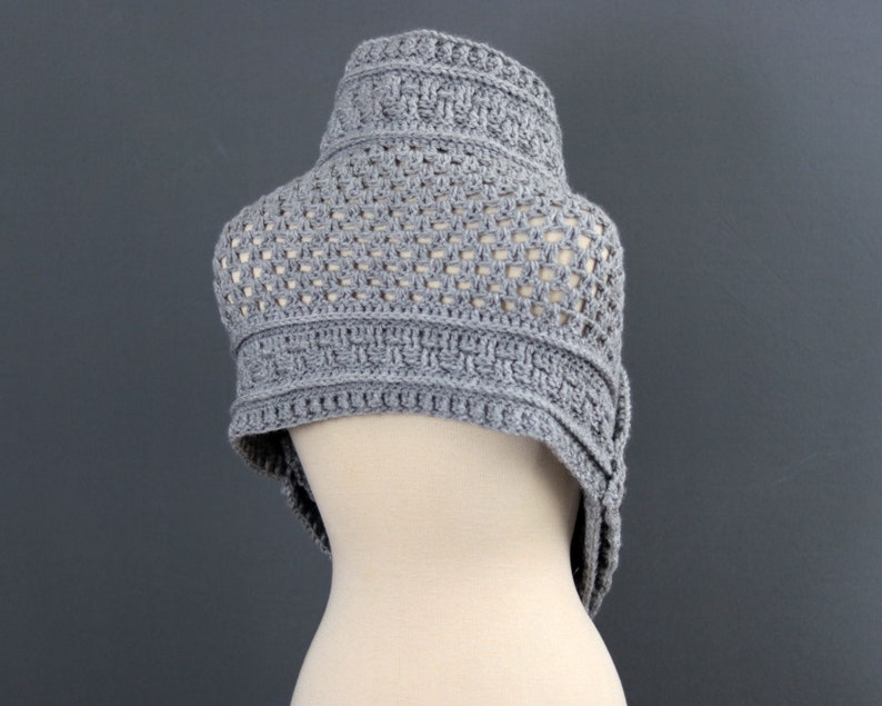 May include: A gray crocheted shawl with a geometric pattern. The shawl is draped over a mannequin.