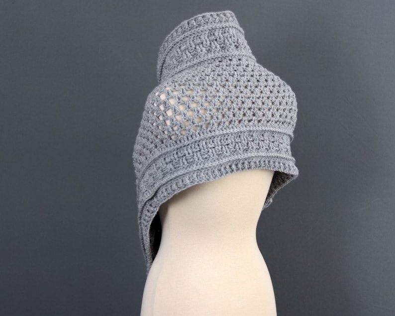 May include: A gray crocheted shawl with a delicate openwork pattern. The shawl is draped over a dress form.