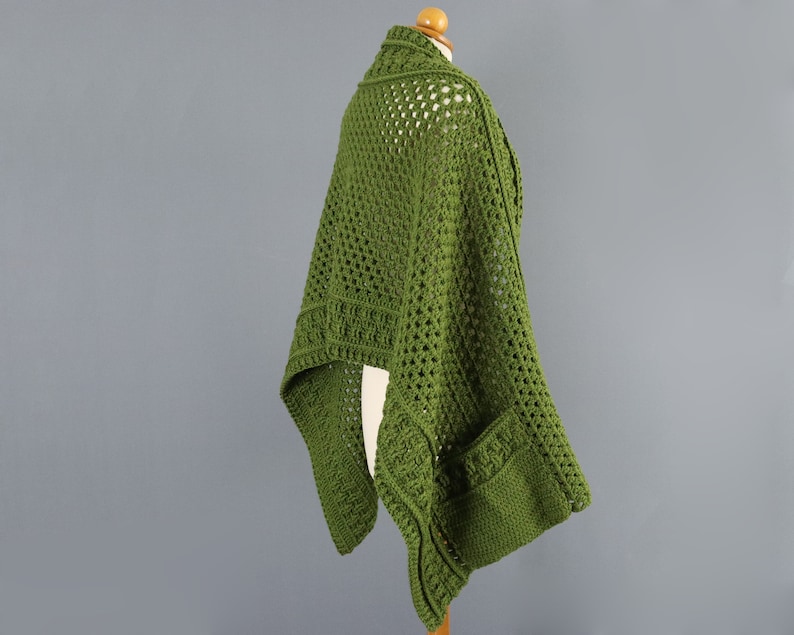 May include: A green crochet shawl with a lacy pattern and a pocket on the side.