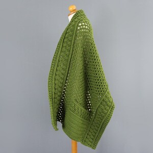 May include: A green crocheted cardigan with a loose fit and open front. The cardigan is made with a textured stitch and has a simple, elegant design.