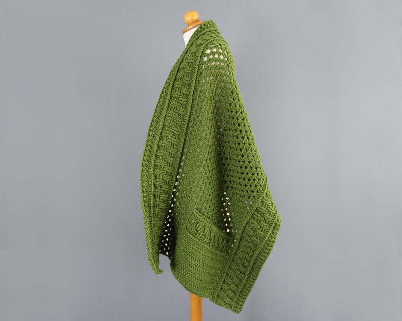May include: A green crocheted cardigan with a loose fit and open front. The cardigan is made with a textured stitch and has a simple, elegant design.