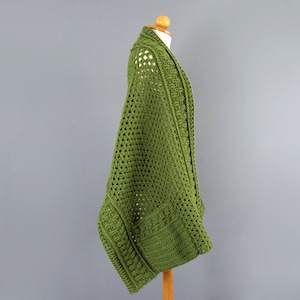 May include: A green crocheted cardigan with a loose fit and a wide open front. The cardigan is made with a delicate open stitch pattern.