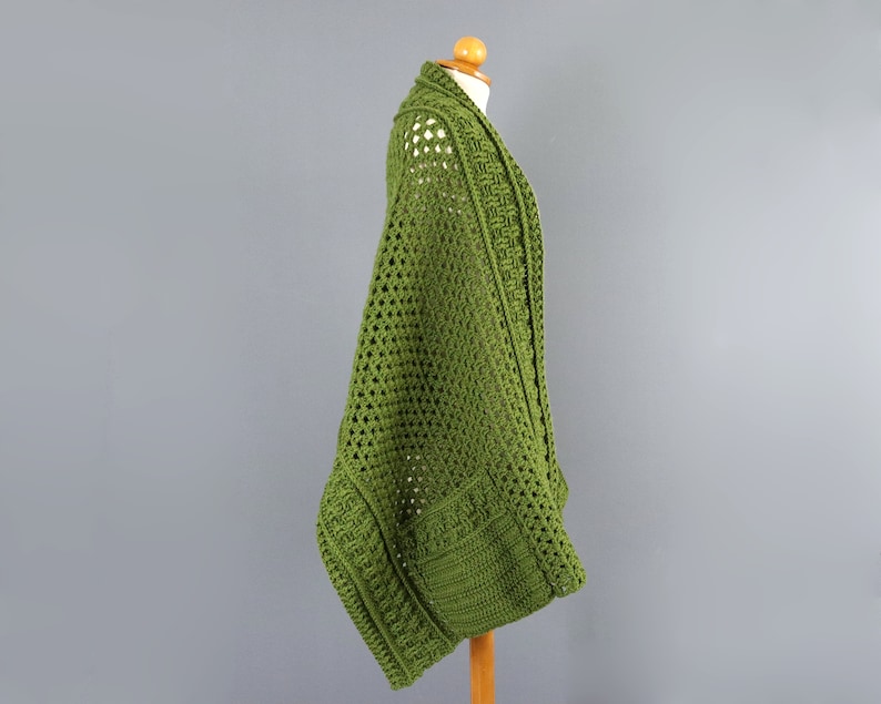 May include: A green crocheted cardigan with a loose fit and a wide open front. The cardigan is made with a delicate open stitch pattern.