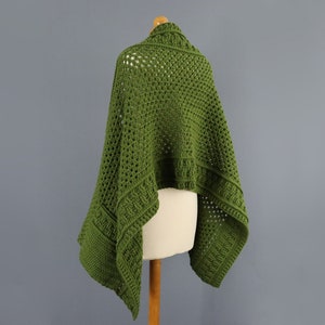 May include: A green crochet shawl with a lacy pattern. The shawl is draped over a dress form.