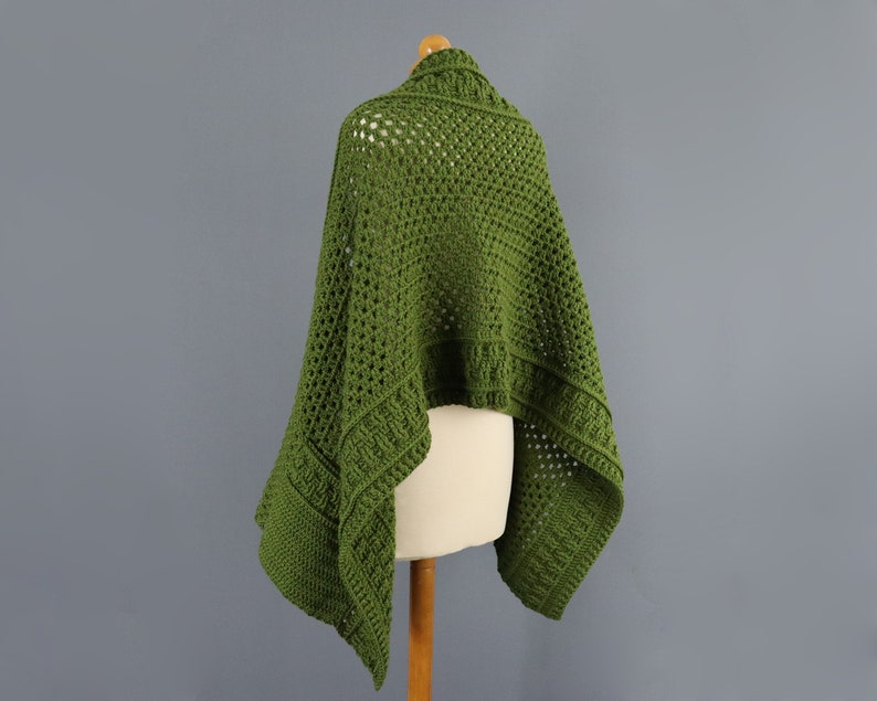 May include: A green crochet shawl with a lacy pattern. The shawl is draped over a dress form.