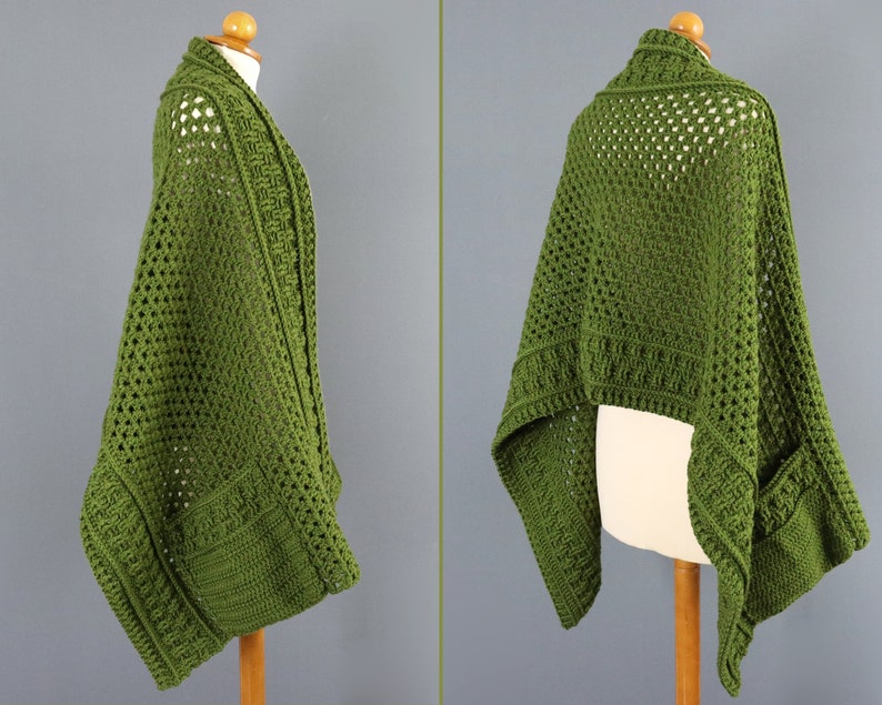 May include: A green crochet shawl with a lacy pattern and pockets. The shawl is draped over a mannequin.